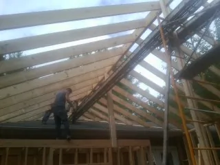 Rafters going up over a new addition with a worker on the wall in Hidden Valley