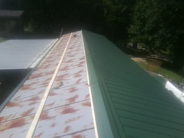 Old rusted panels beside newly installed green metal roofing — Wind Damage Roof Repair by Roofing Brothers in Hidden Valley