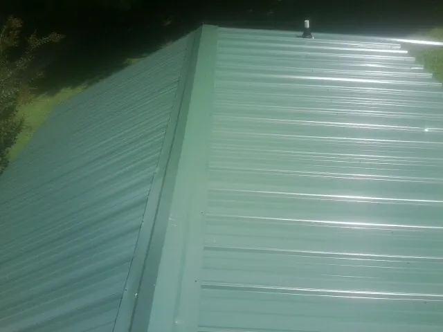 New green metal panels meeting at the ridge of a roof — Flat Roof Repair work by our crew in Hidden Valley