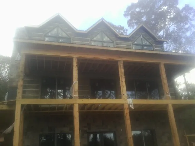 Dormers and porch framing on a large log home under construction — Roof Coating work by our crew in Hidden Valley