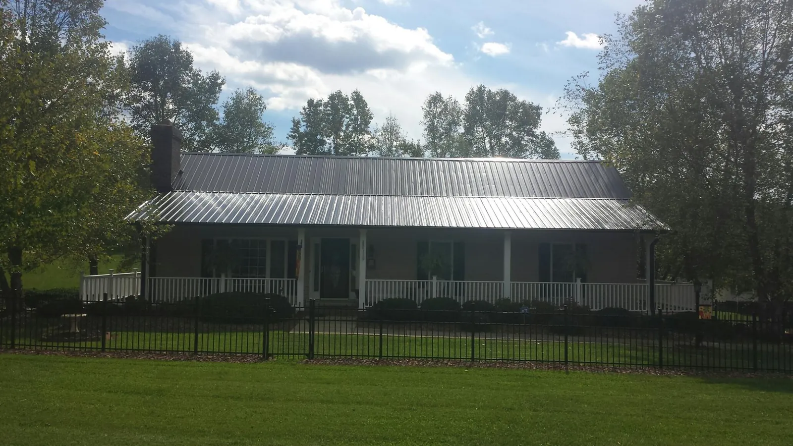 Gray metal roof on a brick ranch with a full width front porch — Gutter Guard Installation work by our crew in Hidden Valley