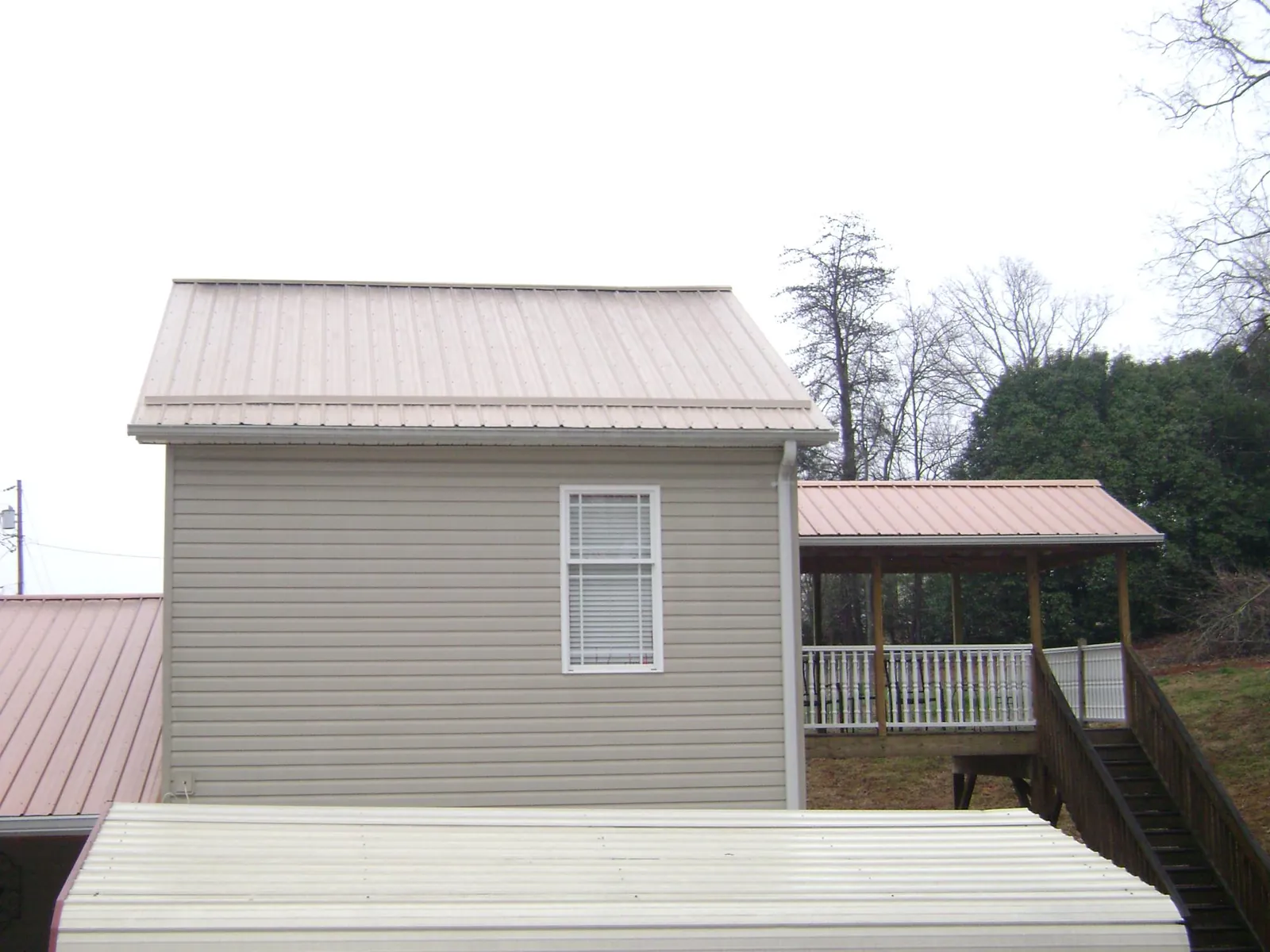Tan metal roofs on a two story addition and attached porch, from a Roof Replacement job in Hidden Valley