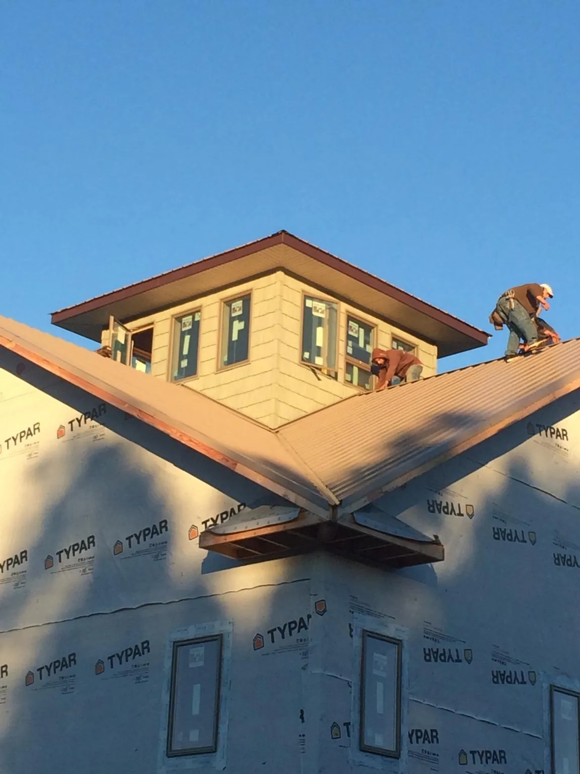 Roofers working around a rooftop cupola on a new metal roof at sunset — Roof Waterproofing in Hidden Valley by Roofing Brothers